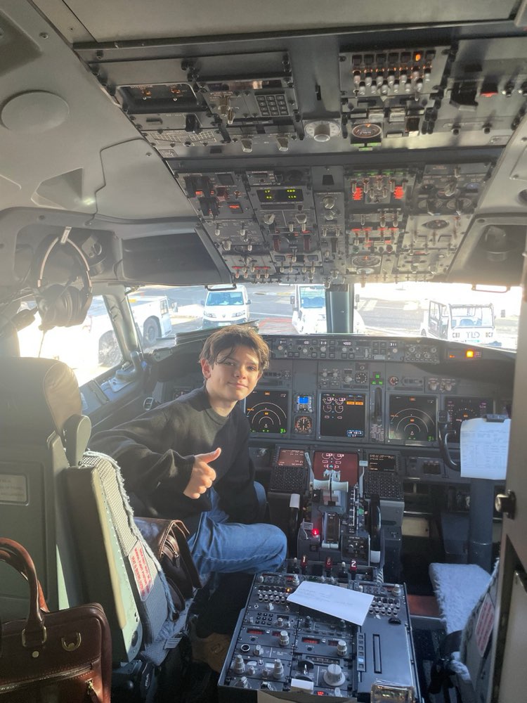 Zack Guerrand in the captain's seat of a Boeing 737 cockpit, giving a thumbs up